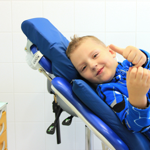 Мальчик показывает палец вверх в кабинете стоматолога